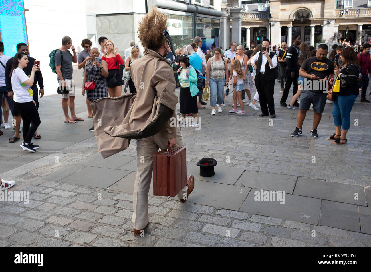 living-statue-street-performer-as-a-commuter-walking-in-the-wind-with-hair-and-clothes-billowing-as-passers-by-look-on-in-covent-garden-in-london-united-kingdom-W95BY2.jpg